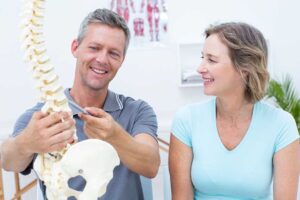 Person resting in bed while a clinician discusses neck pain and sleep posture using a simple diagram
